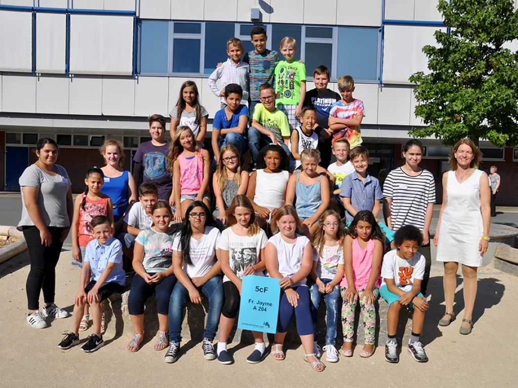Klassenfoto einer neuen fünften Klasse unter Bäumen im Schulhof.